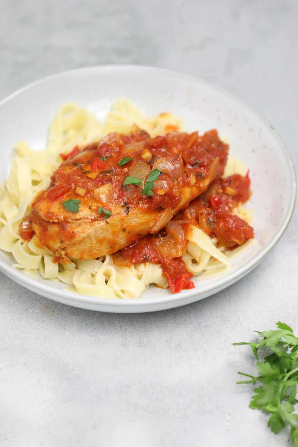 chicken breasts in tomato sauce on pasta.