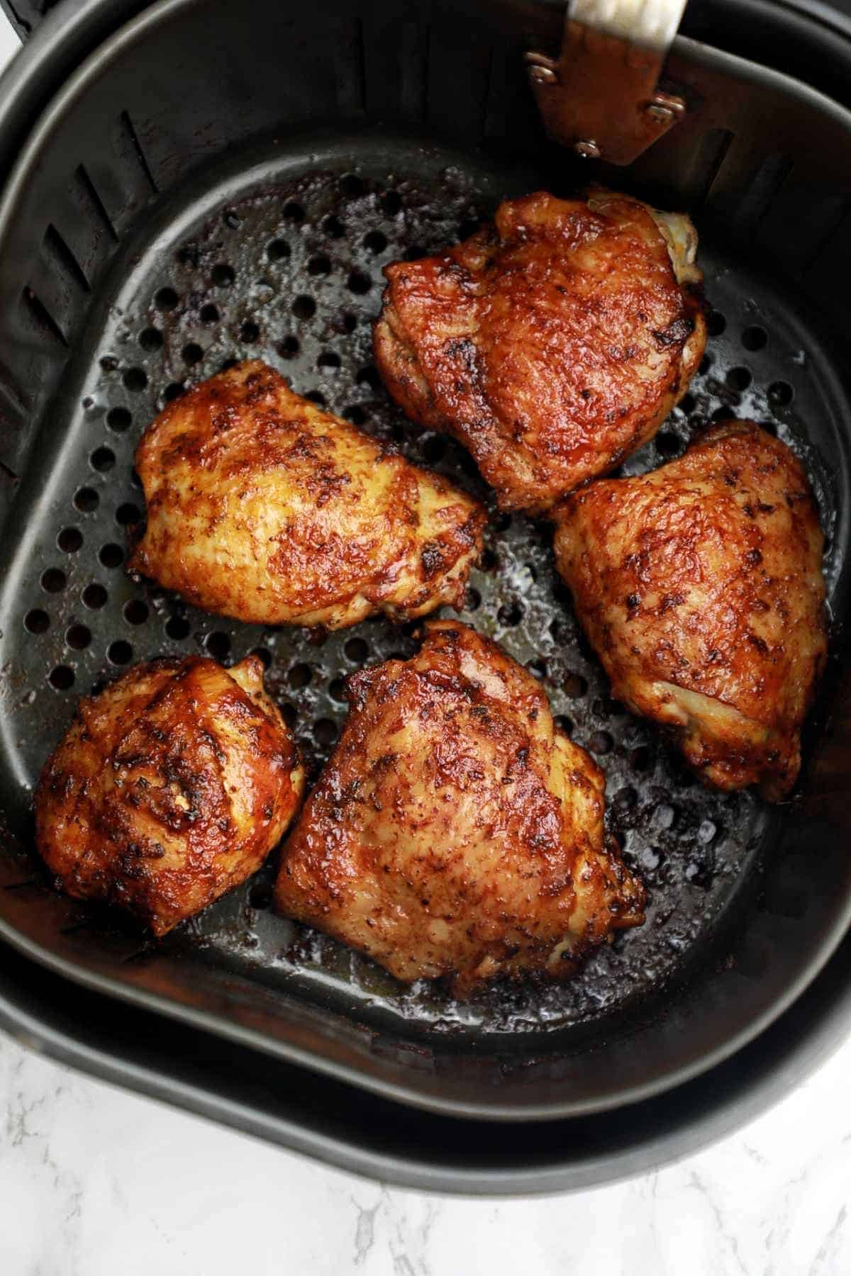 thighs brushed with bbq sauce in air fryer basket.