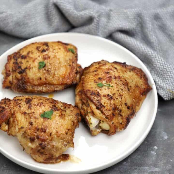 pan fried chicken thighs served on a plate.