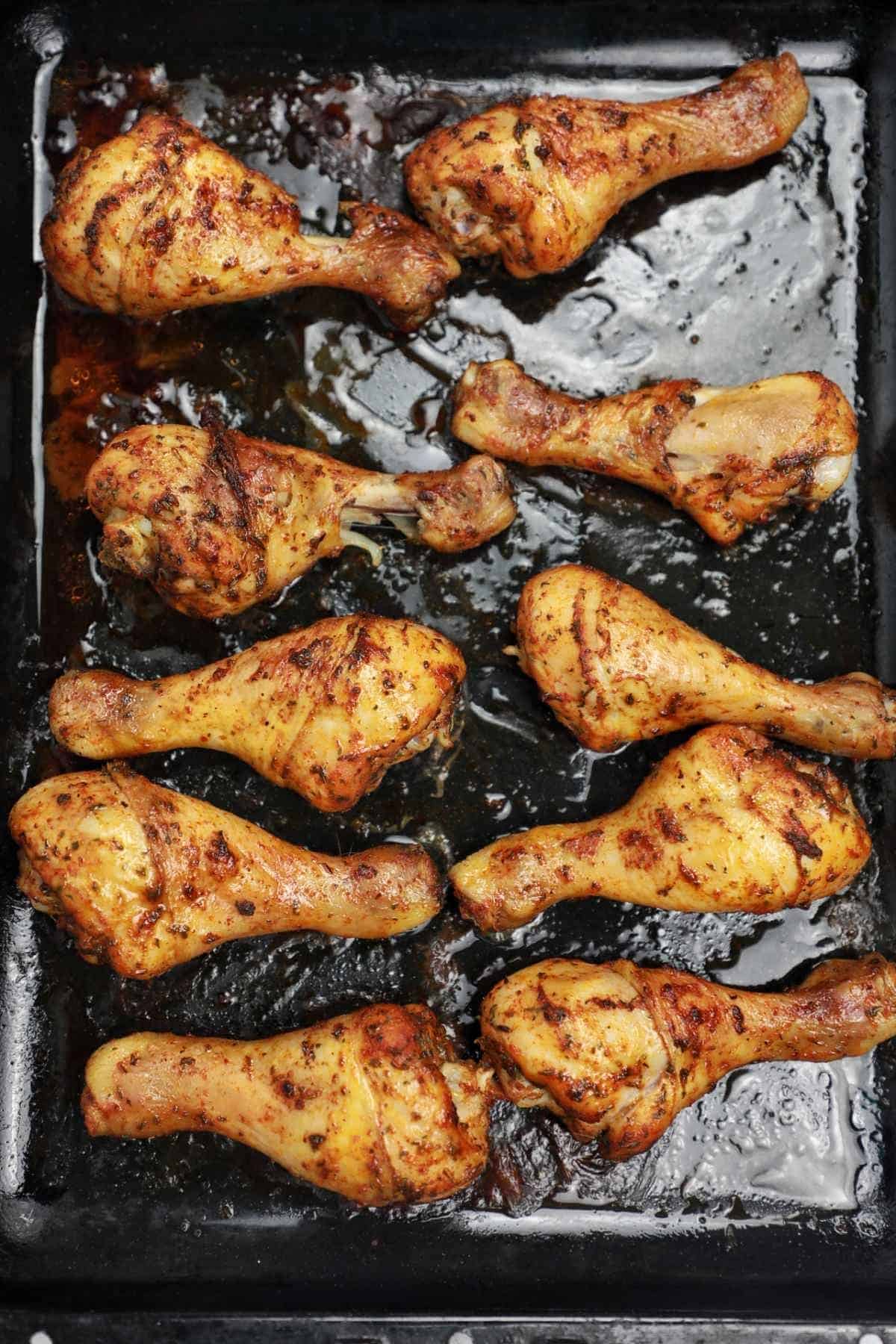 Baked chicken drumsticks on a tray.