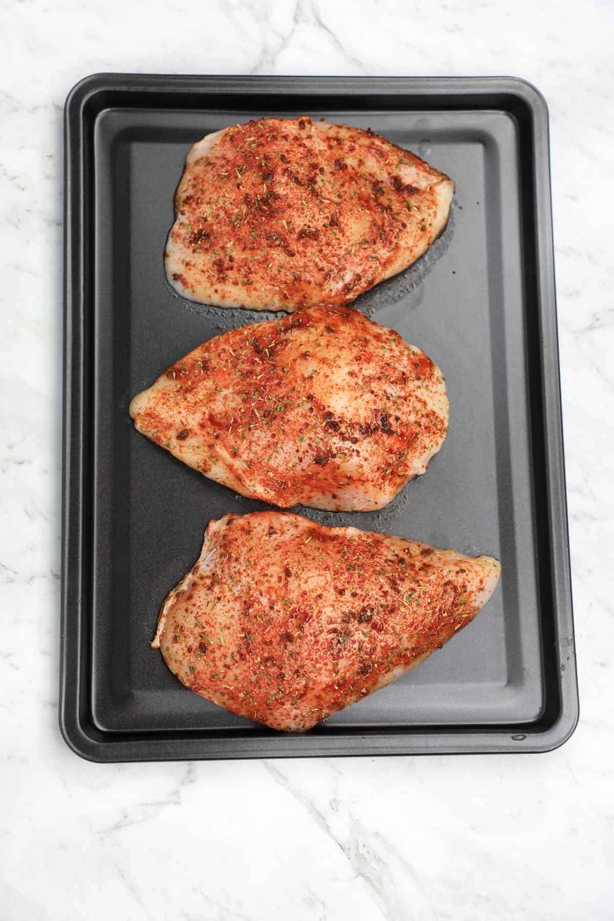 seasoned pieces arranged on a baking tray.