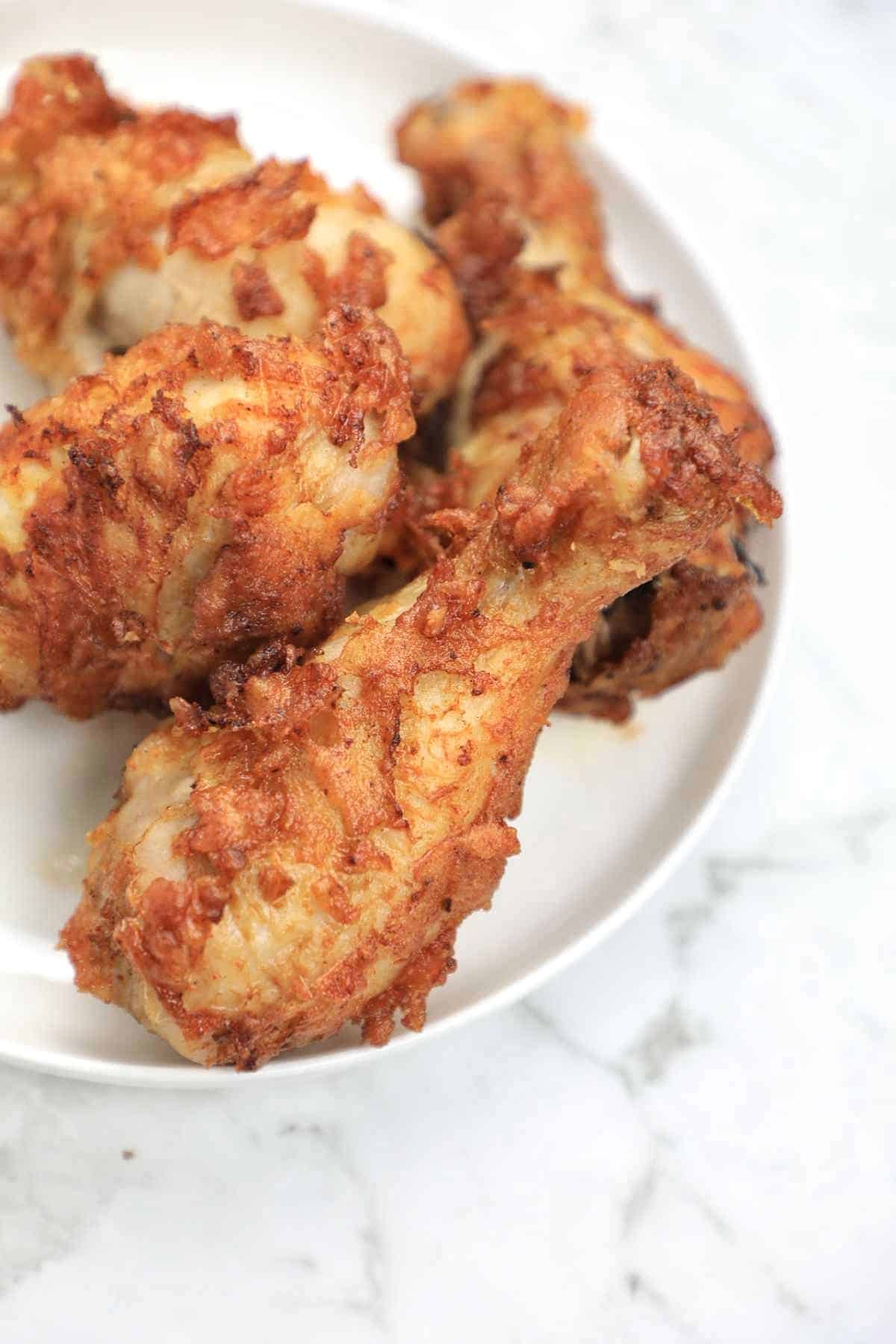 deep fried chicken drumsticks served on a white plate.