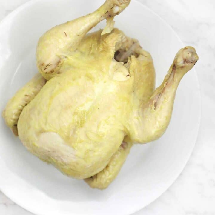 boiled whole chicken on a white plate.