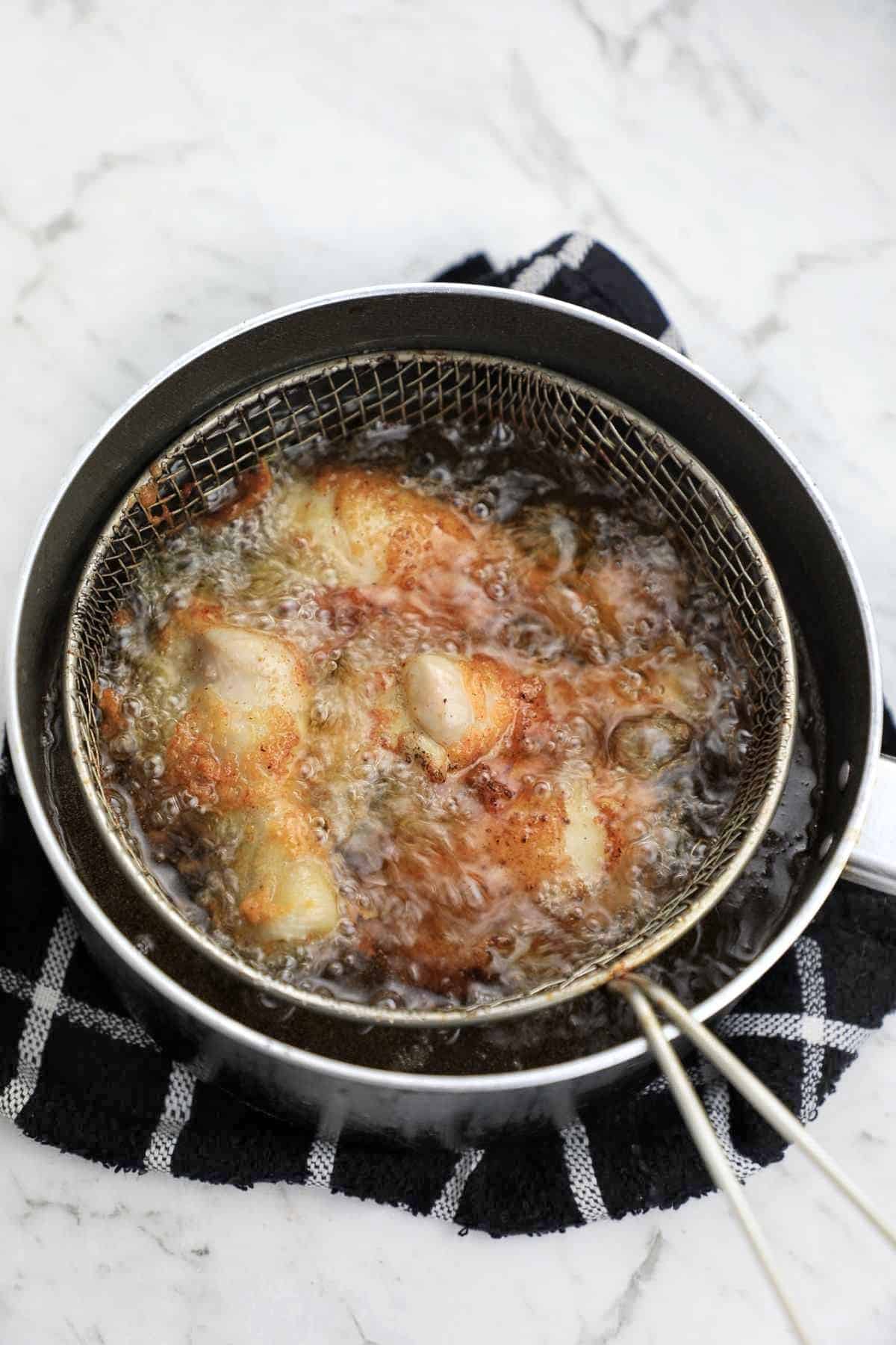 frying chicken legs in a chip pan.