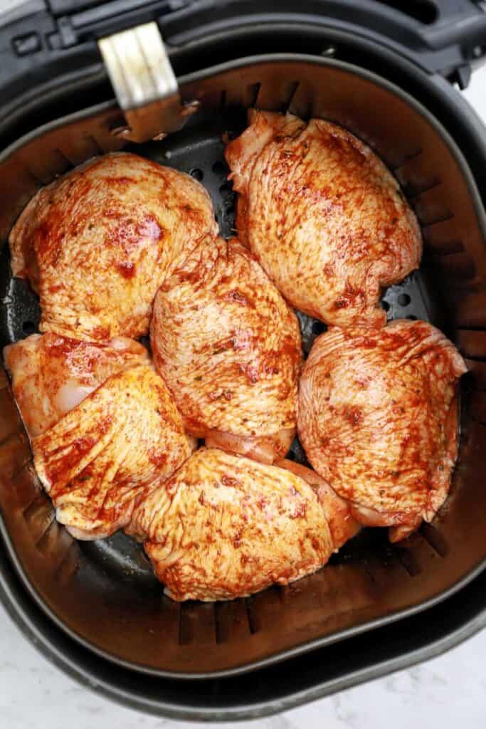 chicken thighs arranged in air fryer basket.