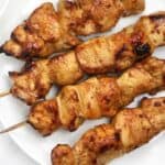 chicken on skewers displayed on a white plate.