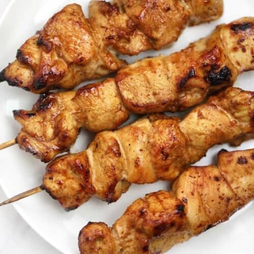 chicken on skewers displayed on a white plate.