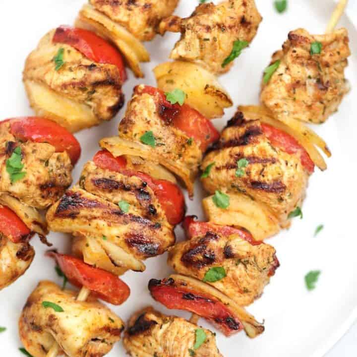 chicken skewers on a white plate.