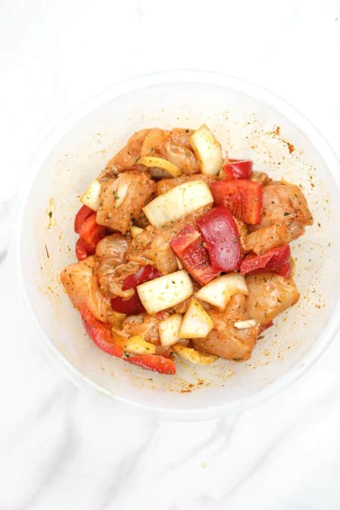 marinated chicken, peppers, and onions in a bowl.