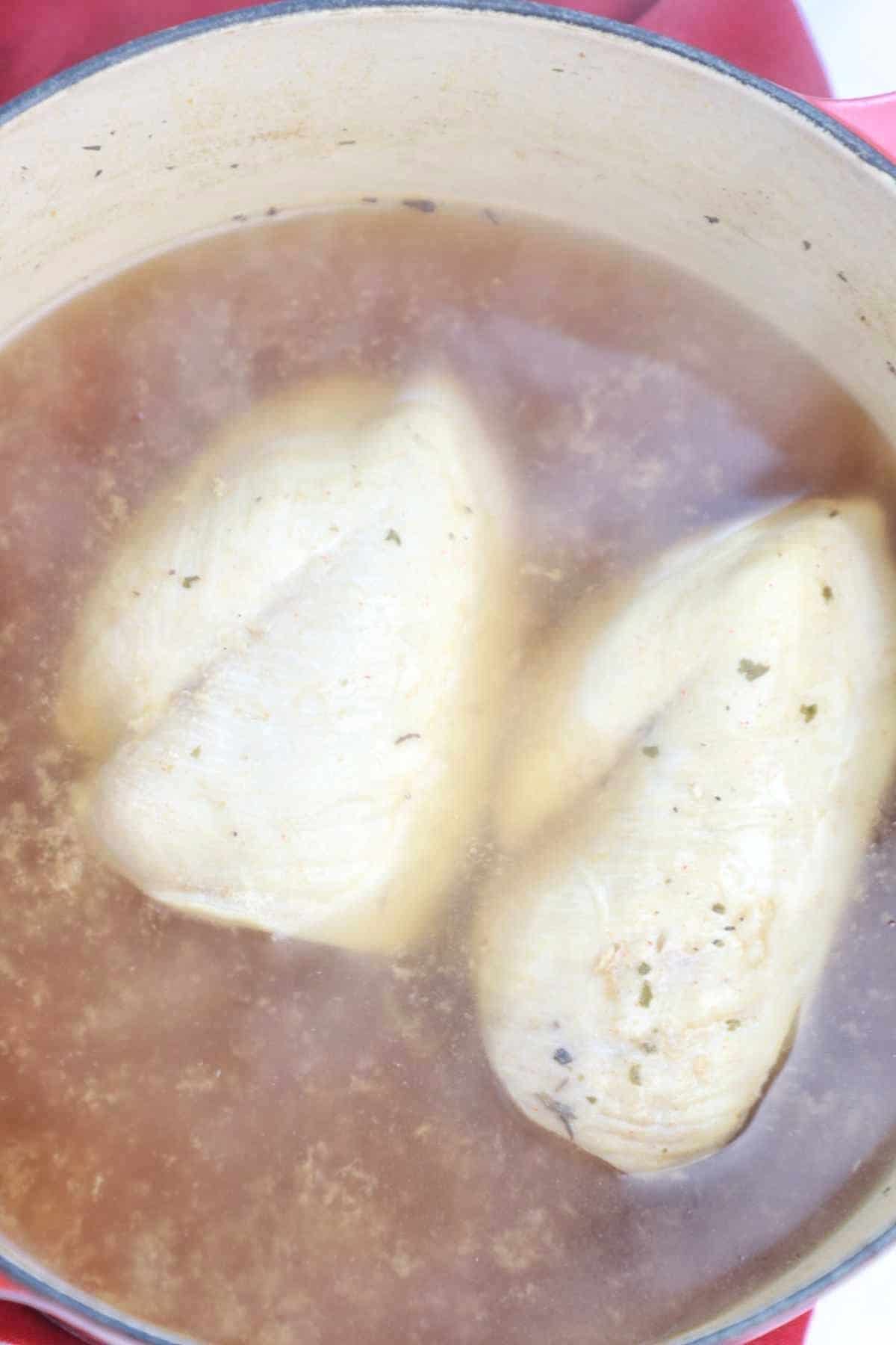 boiled frozen chicken and broth in a pot.