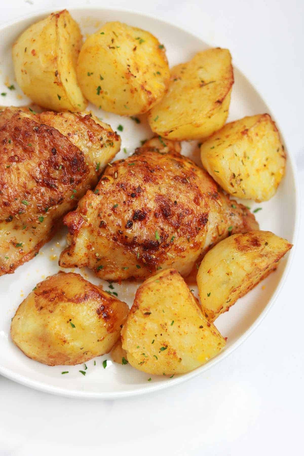 baked chicken and potatoes served on a white plate.