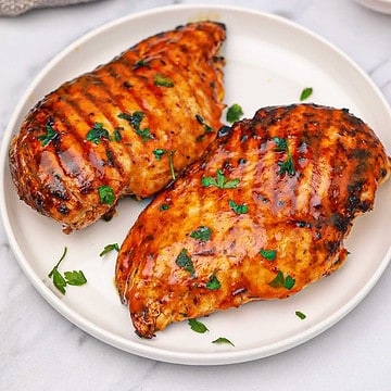 2 buffalo chicken breasts served on a plate and garnished with parsley.