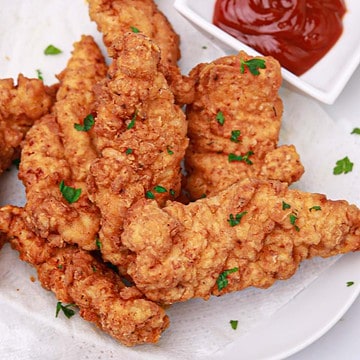 the fried chicken tenders on a plate with ketchup dip.