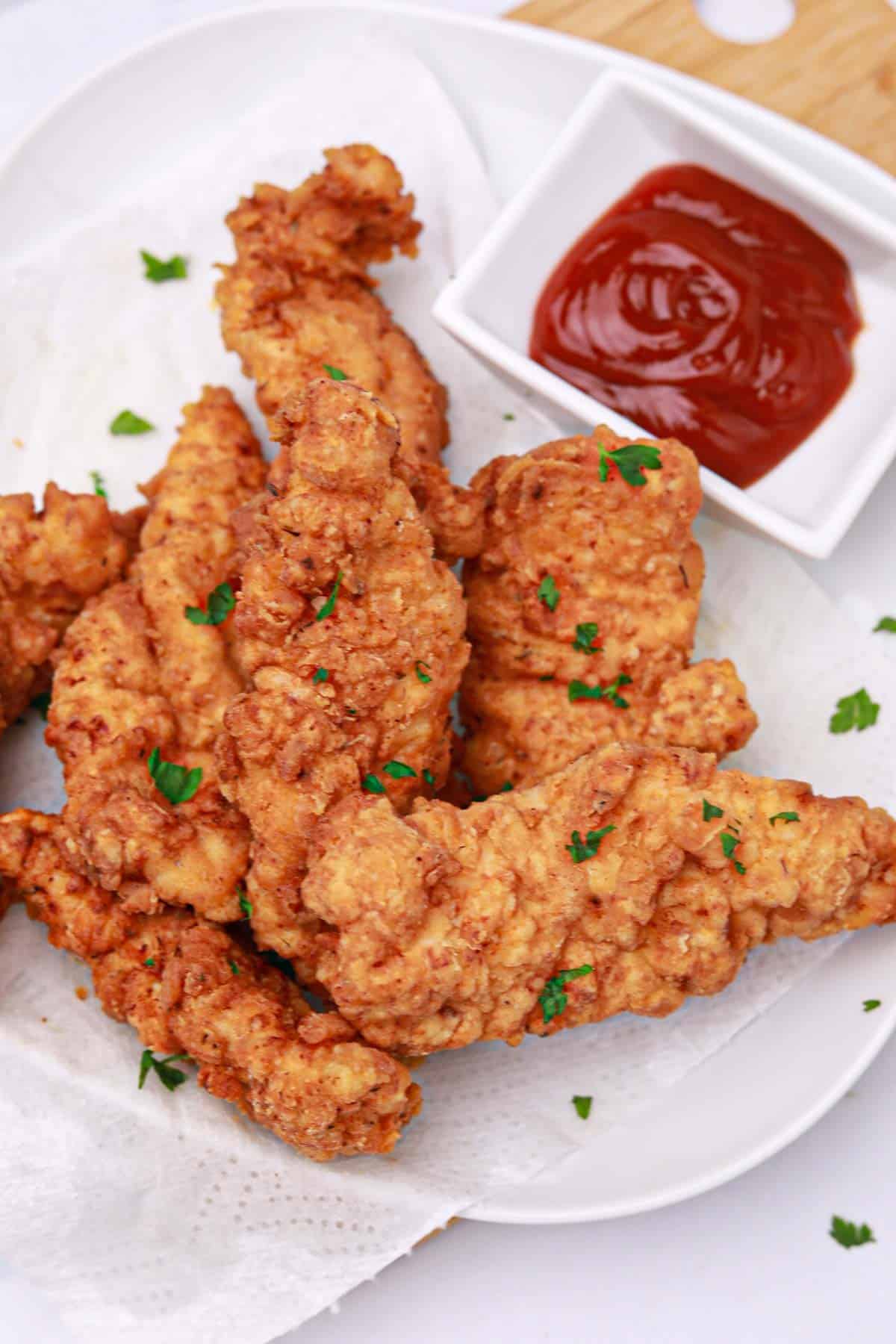 the fried chicken tenders on a plate with ketchup dip.