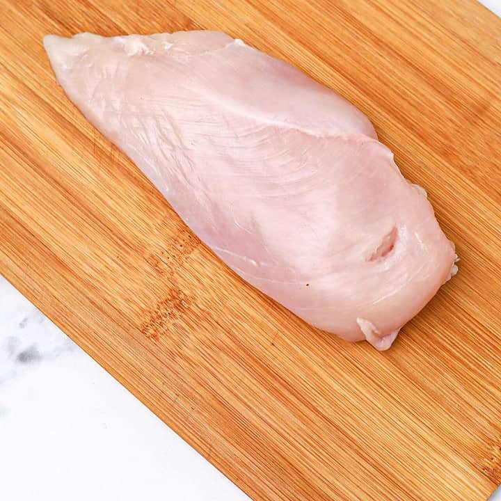 A chicken breast on a cutting board.