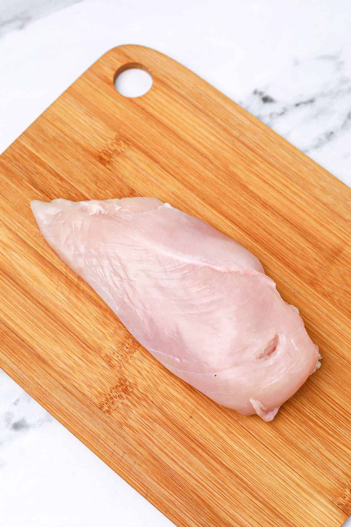 A chicken breast on a cutting board.
