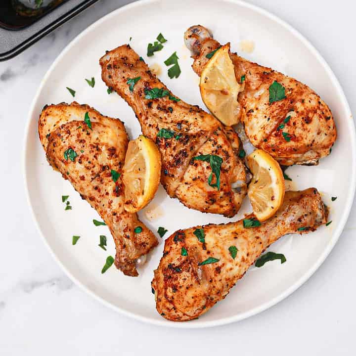 lemon pepper chicken drumsticks on a plate and in baking tray.