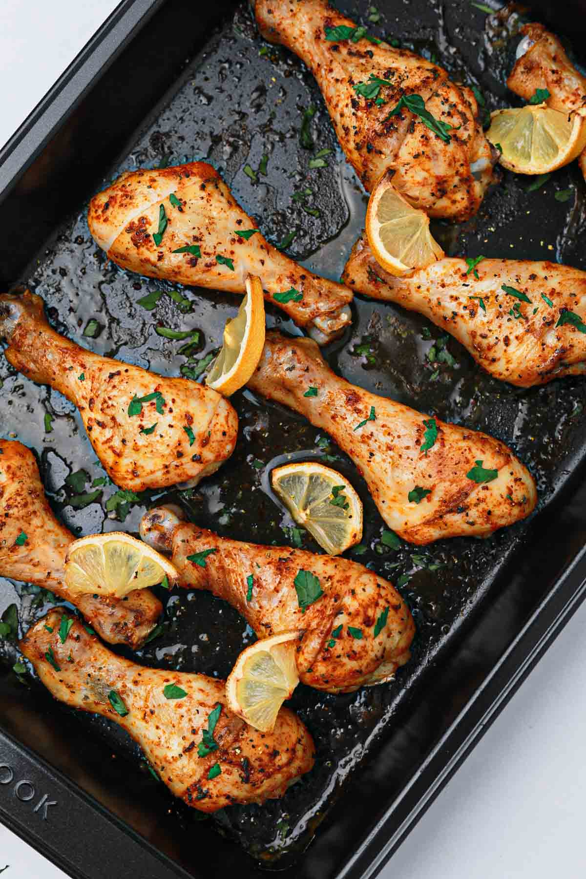 cooked lemon pepper chicken drumsticks on a baking tray.