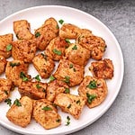 chicken pieces served on a plate and garnished with parsley.